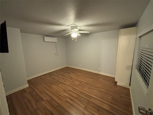 basement featuring an AC wall unit, ceiling fan, dark hardwood / wood-style flooring, and a textured ceiling