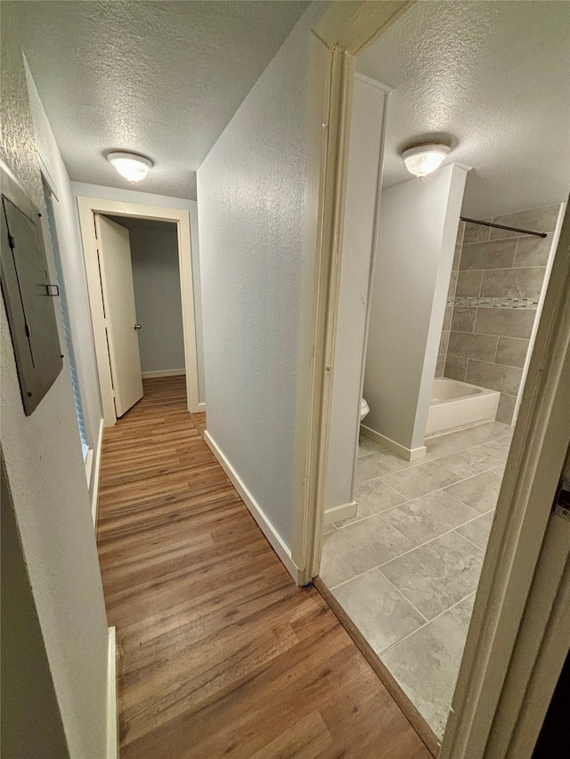 hall with light wood-type flooring and a textured ceiling