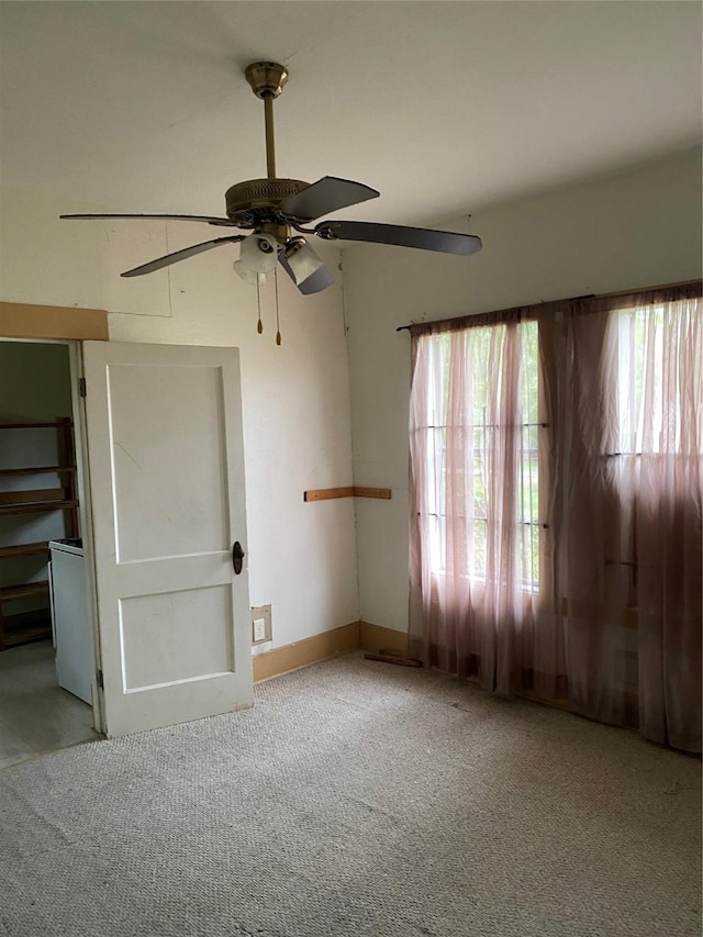 carpeted empty room with ceiling fan and plenty of natural light