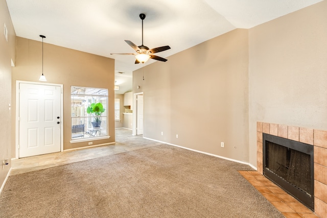 unfurnished living room featuring a tile fireplace, carpet flooring, high vaulted ceiling, and ceiling fan