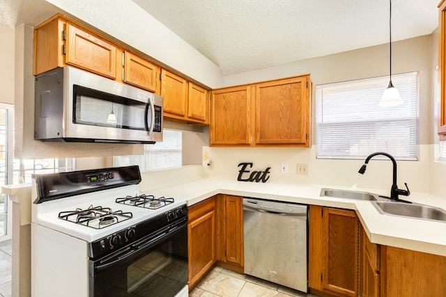 kitchen featuring sink, a textured ceiling, decorative light fixtures, light tile patterned flooring, and stainless steel appliances