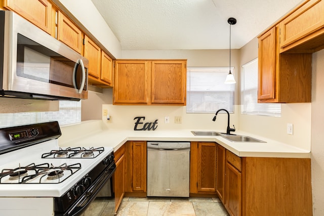 kitchen with decorative light fixtures, a textured ceiling, stainless steel appliances, and sink