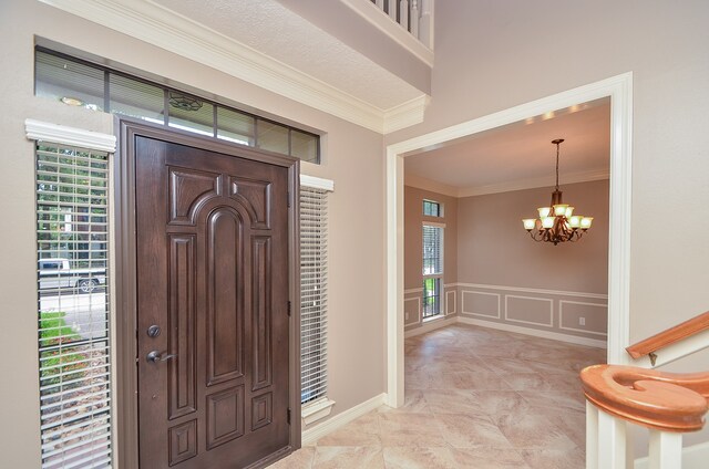 foyer with a notable chandelier and crown molding