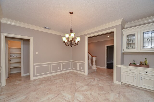 unfurnished dining area with ornamental molding, a textured ceiling, and a chandelier