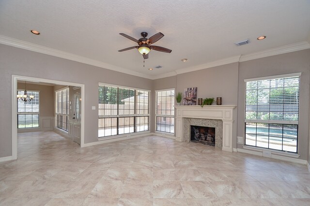 unfurnished living room featuring ceiling fan with notable chandelier, ornamental molding, and a textured ceiling