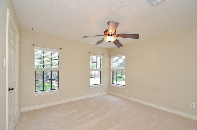 spare room with ceiling fan, light colored carpet, and a wealth of natural light