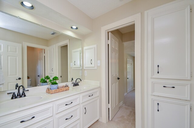 bathroom with a textured ceiling, vanity, and toilet