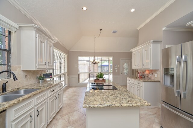 kitchen with white cabinets, a center island, stainless steel fridge, and a healthy amount of sunlight