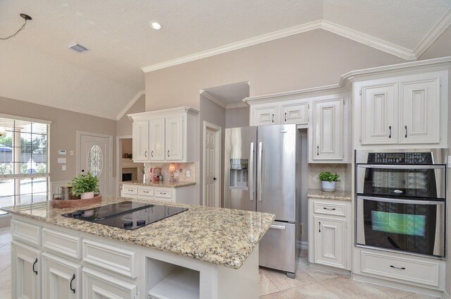 kitchen featuring a center island, tasteful backsplash, lofted ceiling, white cabinets, and appliances with stainless steel finishes