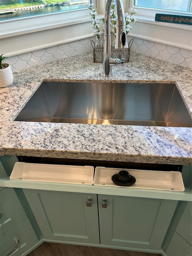 interior details with light stone countertops, sink, and green cabinetry