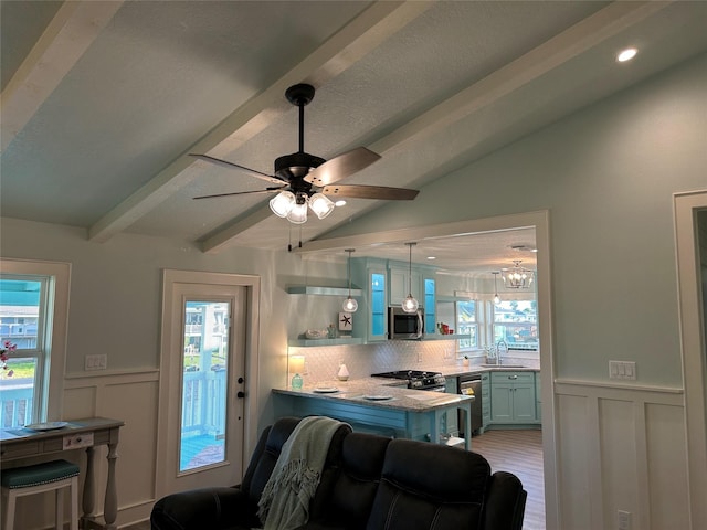 kitchen with sink, appliances with stainless steel finishes, lofted ceiling with beams, a kitchen bar, and decorative backsplash