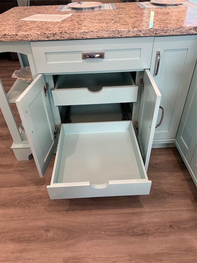 details featuring light stone countertops, dark hardwood / wood-style floors, and green cabinets