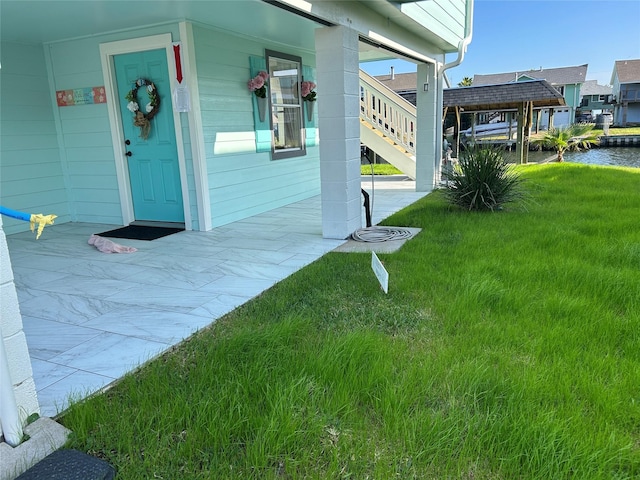 view of exterior entry with a water view and a lawn