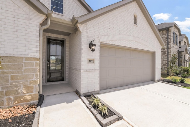 property entrance featuring brick siding, concrete driveway, and a garage