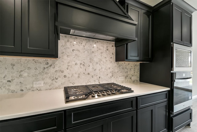 kitchen featuring oven, light countertops, backsplash, extractor fan, and stainless steel gas cooktop
