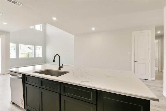 kitchen featuring light wood finished floors, stainless steel dishwasher, a sink, visible vents, and an island with sink