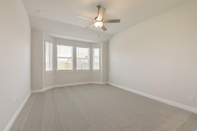 spare room featuring vaulted ceiling, a ceiling fan, baseboards, and light carpet