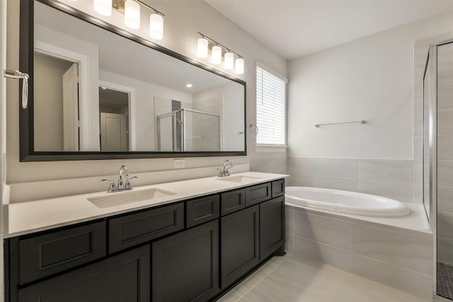 full bath with a bath, a sink, a shower stall, and tile patterned flooring