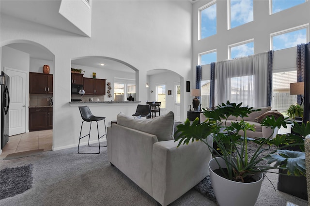 carpeted living room featuring a towering ceiling