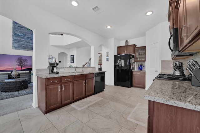 kitchen with sink, light stone counters, and black appliances