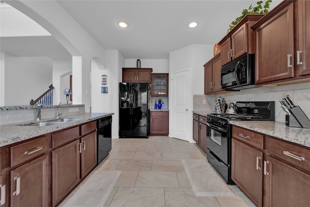 kitchen with sink, backsplash, light stone counters, and black appliances