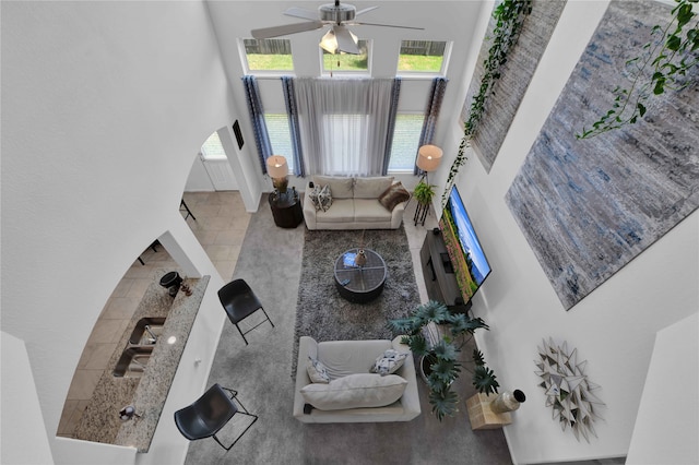 tiled living room featuring ceiling fan and a towering ceiling