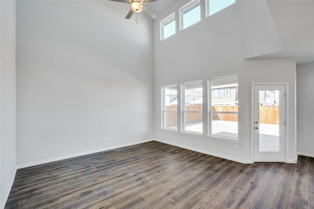 unfurnished living room with a towering ceiling, dark hardwood / wood-style flooring, and plenty of natural light