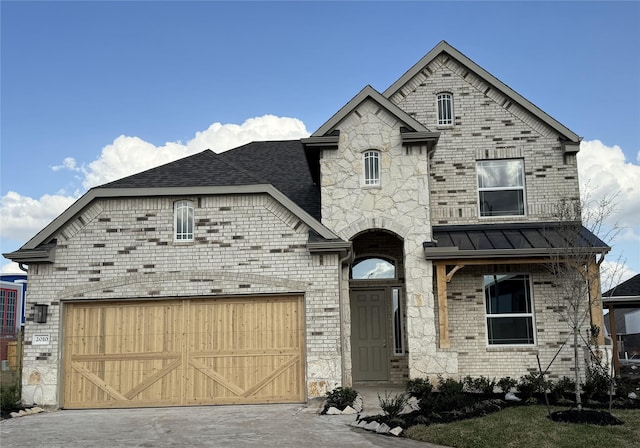 french provincial home featuring metal roof, brick siding, a garage, and a standing seam roof