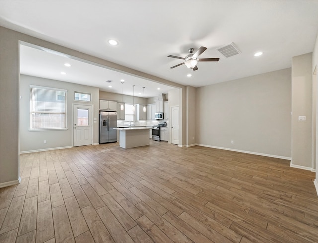 unfurnished living room featuring ceiling fan and light hardwood / wood-style flooring