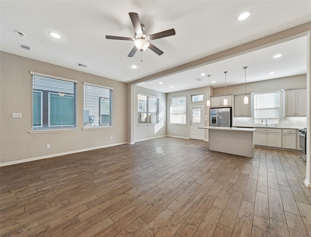 unfurnished living room featuring hardwood / wood-style floors, ceiling fan, and sink