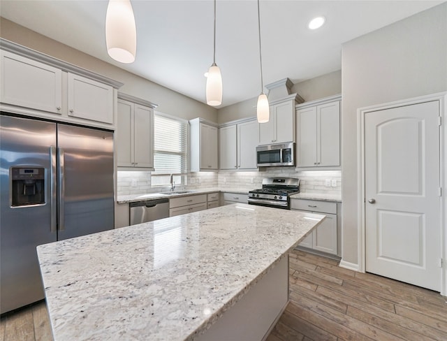 kitchen featuring a center island, sink, hanging light fixtures, light hardwood / wood-style flooring, and appliances with stainless steel finishes