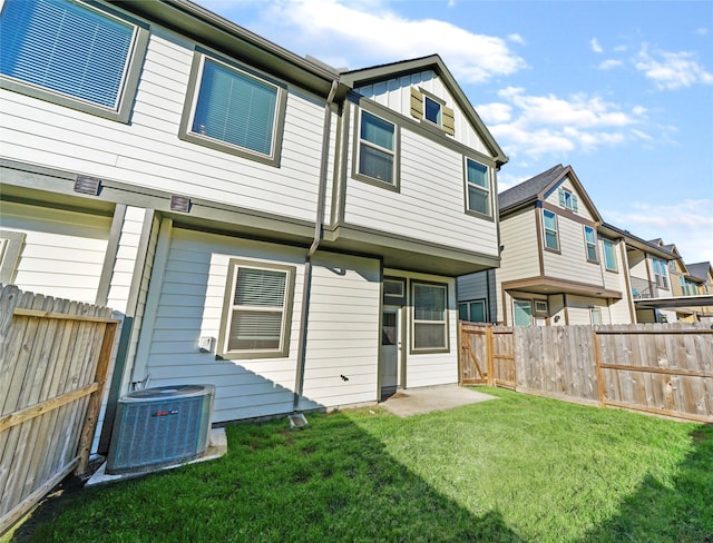 rear view of property featuring central AC unit and a lawn