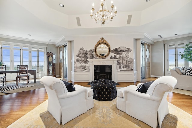 living room with light hardwood / wood-style floors, a tray ceiling, crown molding, and a notable chandelier