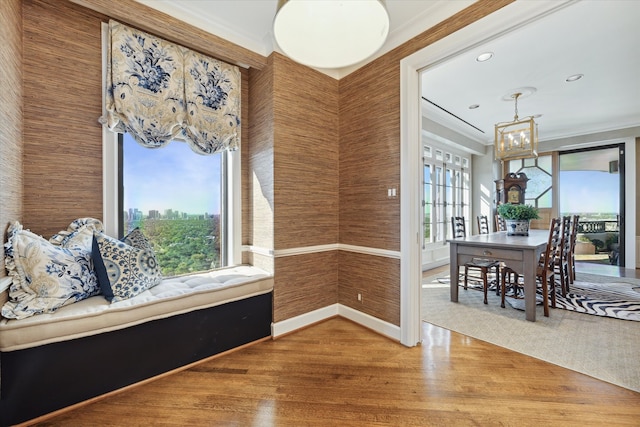 sitting room with wood-type flooring, an inviting chandelier, and crown molding