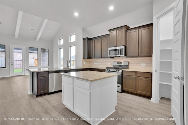 kitchen with sink, a kitchen island, light wood-type flooring, and appliances with stainless steel finishes