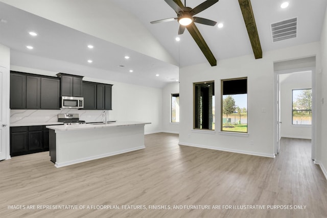 kitchen with ceiling fan, light hardwood / wood-style flooring, an island with sink, a healthy amount of sunlight, and appliances with stainless steel finishes