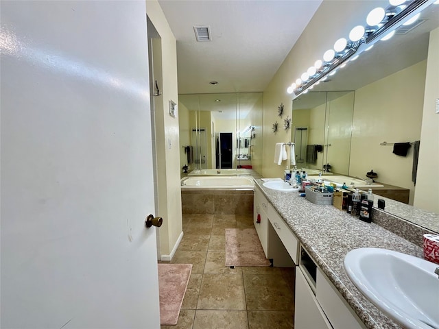 bathroom with tile patterned floors, vanity, and tiled bath