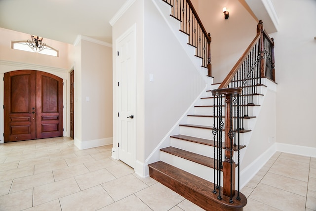 entrance foyer with light tile patterned floors, crown molding, and a notable chandelier