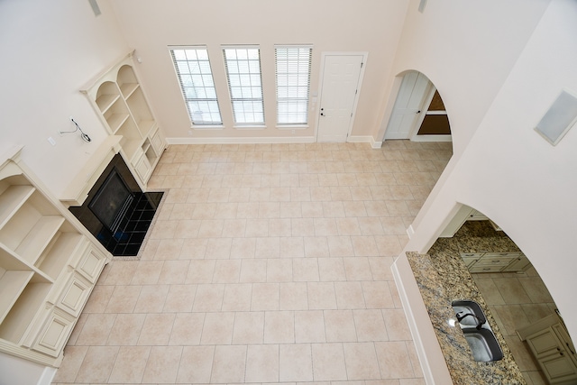 unfurnished living room featuring a towering ceiling and light tile patterned floors