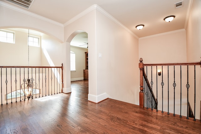 corridor featuring wood-type flooring, crown molding, and an inviting chandelier