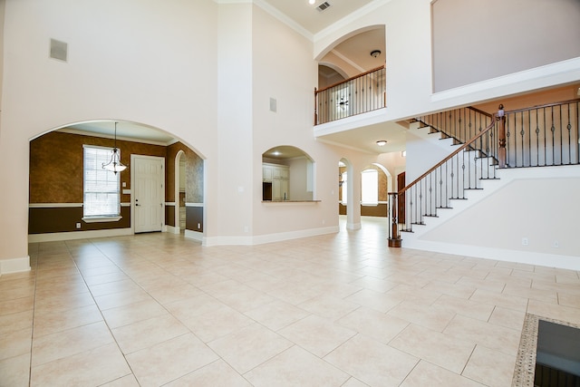 entrance foyer featuring light tile patterned flooring, a towering ceiling, ornamental molding, and decorative columns