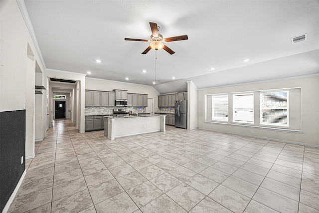 kitchen with lofted ceiling, gray cabinets, ornamental molding, an island with sink, and stainless steel appliances