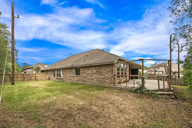 rear view of property with a lawn and a wooden deck