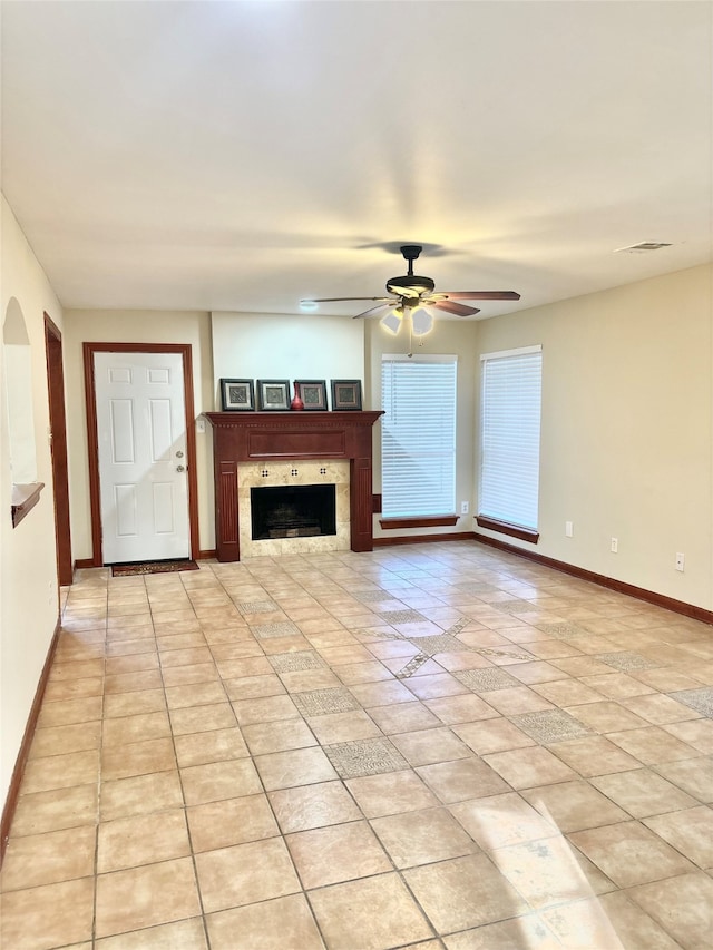 unfurnished living room with light tile patterned flooring, ceiling fan, and a tiled fireplace