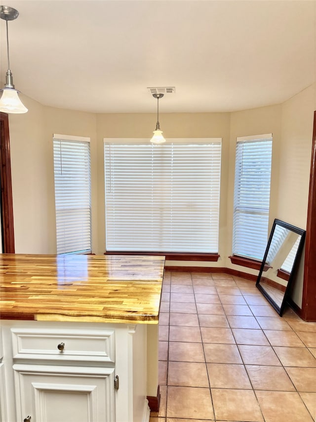 kitchen featuring light tile patterned floors, decorative light fixtures, and wood counters