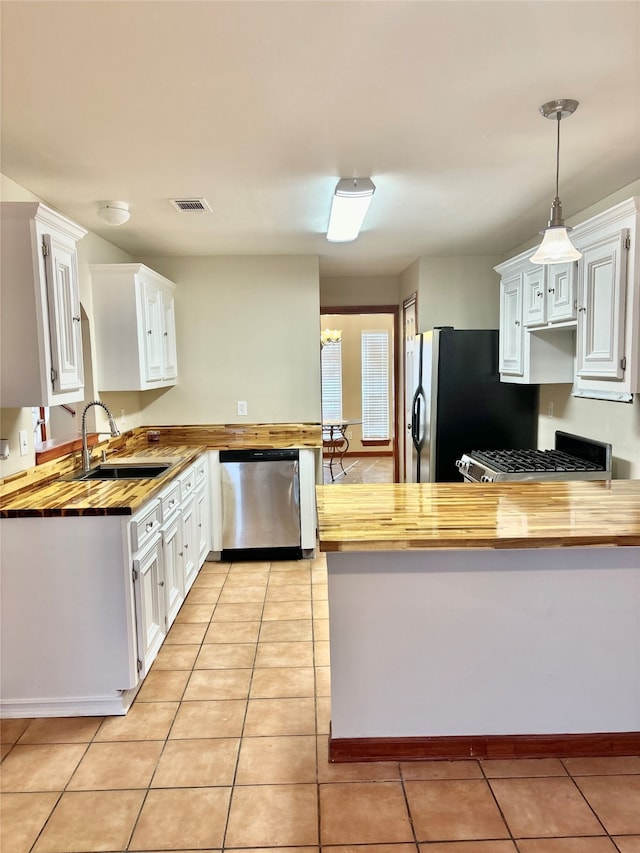 kitchen with white cabinets, pendant lighting, stainless steel appliances, and butcher block counters