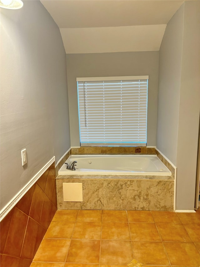 bathroom with tile patterned floors, tiled tub, and vaulted ceiling