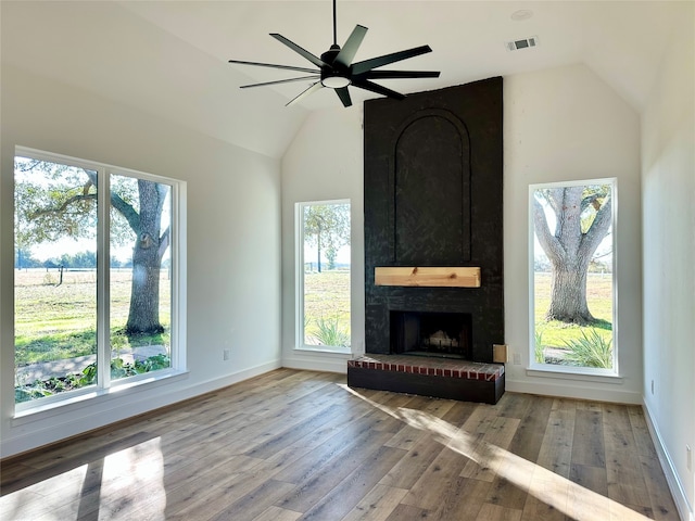 unfurnished living room with ceiling fan, a fireplace, high vaulted ceiling, and light wood-type flooring