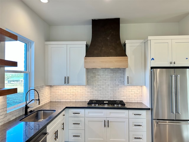 kitchen with sink, stainless steel appliances, premium range hood, backsplash, and white cabinets