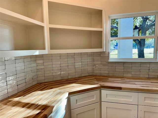 kitchen with tasteful backsplash, white cabinetry, and wood counters